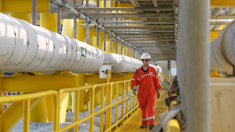 海上生产人员穿过平台间栈桥进行设备巡检。