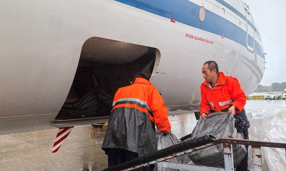 中航集团国货航货站事业部提前做好货物苫盖和防潮工作，一线工作人员在确保安全的前提下搬运货物。
