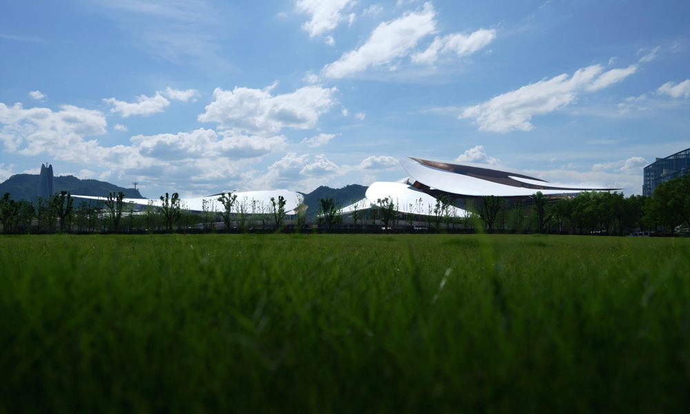 安吉文化艺术中心项目底层微抬形成地景建筑，裙房之上是自由漫步的茶田屋面，建筑与周边竹林、茶山、溪流共同形成有机整体，创造了一个与自然溪畔相连的景观公园。项目将绿色生态与城市景观相融合，践行“绿水青山就是金山银山”重要理念，打造中国传统文化与现代科技创新相结合的建筑典范。