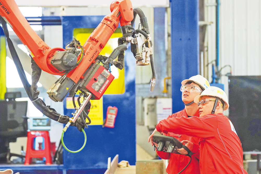 柔性制造智能焊接机器人的研发涉及机械工程、人工智能、传感等多学科交叉技术，对智能决策、环境感知和控制系统等要求都非常高，目前国际上仅有少数国家掌握该项关键技术。图为海油工程“智能焊接突击队”技术人员调试焊接机器人。