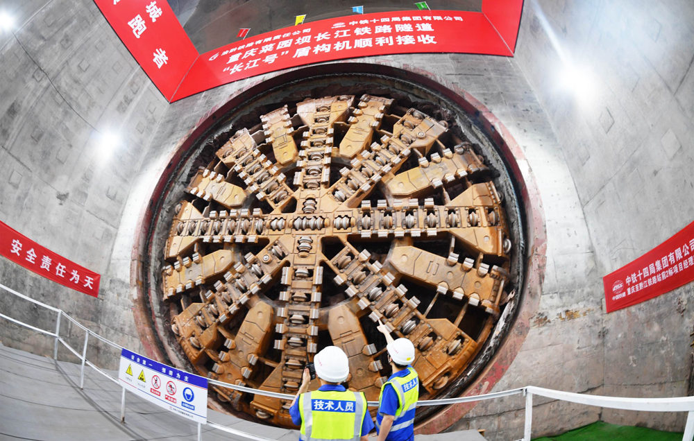 重庆菜园坝长江铁路隧道是渝厦高铁全线关键控制性工程。隧道位于重庆市渝中区与南岸区，为单洞双线高速铁路隧道，全长11942米，起始于重庆火车站，沿途下穿市政道路、高架桥梁、轨道交通线、多处建筑群、长江主航道及南山山体，整体呈现“穿山、穿城、穿江、穿水”的复杂特点，施工难度大、技术要求极高。图为技术人员检查刀盘磨损情况。