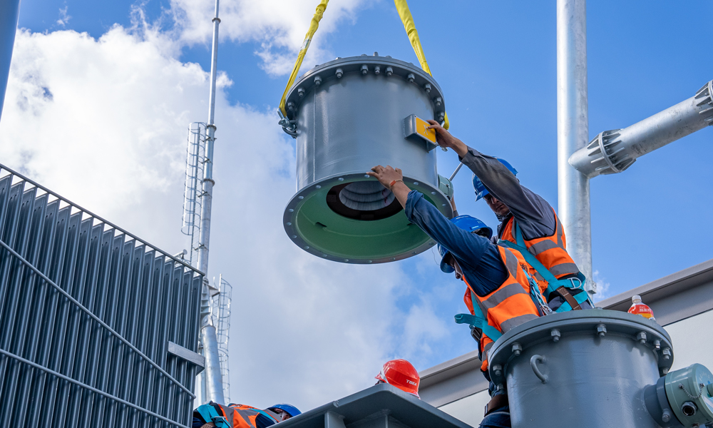 中老500千伏联网工程老挝段包括新建一座变电站及32.5公里线路，计划于2026年4月投产。目前，变电站主体结构及“三通一平”已完成，主要设备全部到场，正进行电气安装。图为施工人员开展主变套管底座安装作业。 