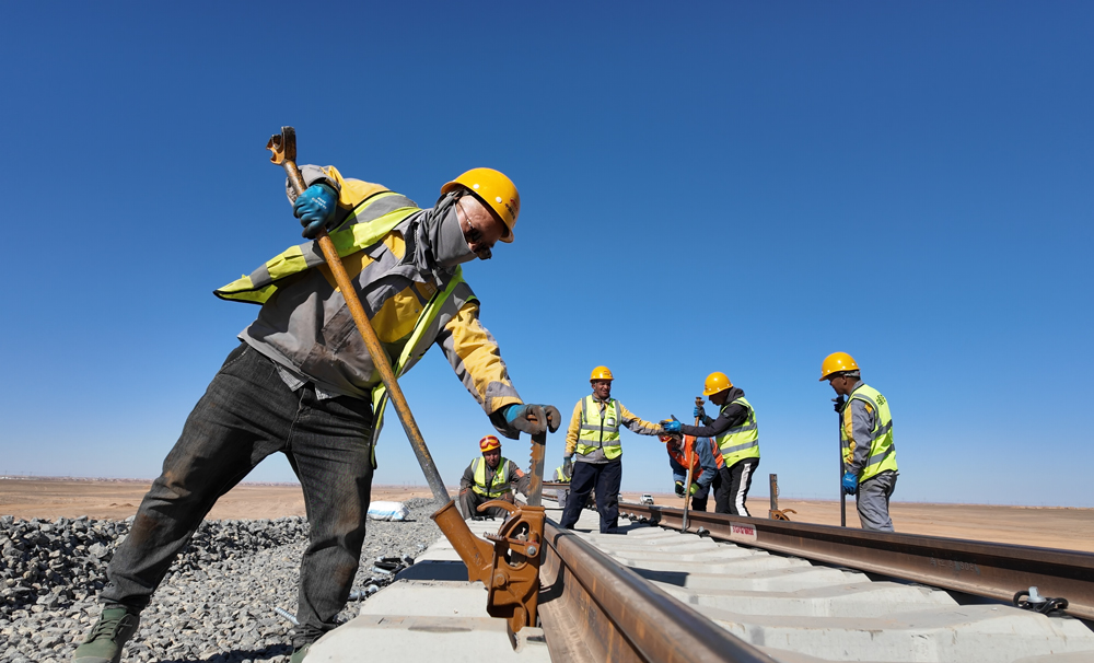 项目通车后将完善阿尔及利亚国家铁路网，助力该国南部省份互联互通，助力当地矿业发展。图为中阿建设者进行铺轨作业。