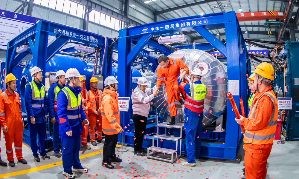 据中铁十四局甬舟铁路项目现场负责人介绍，作业人员进入与外部隔绝的“深海空间站”后，居住在生活舱里，相当于在海底“安家”，每天乘坐穿梭舱到达海底的盾构机上，直接进入高压作业面进行设备维护和刀具更换。图为饱和潜水作业人员顺利出舱。